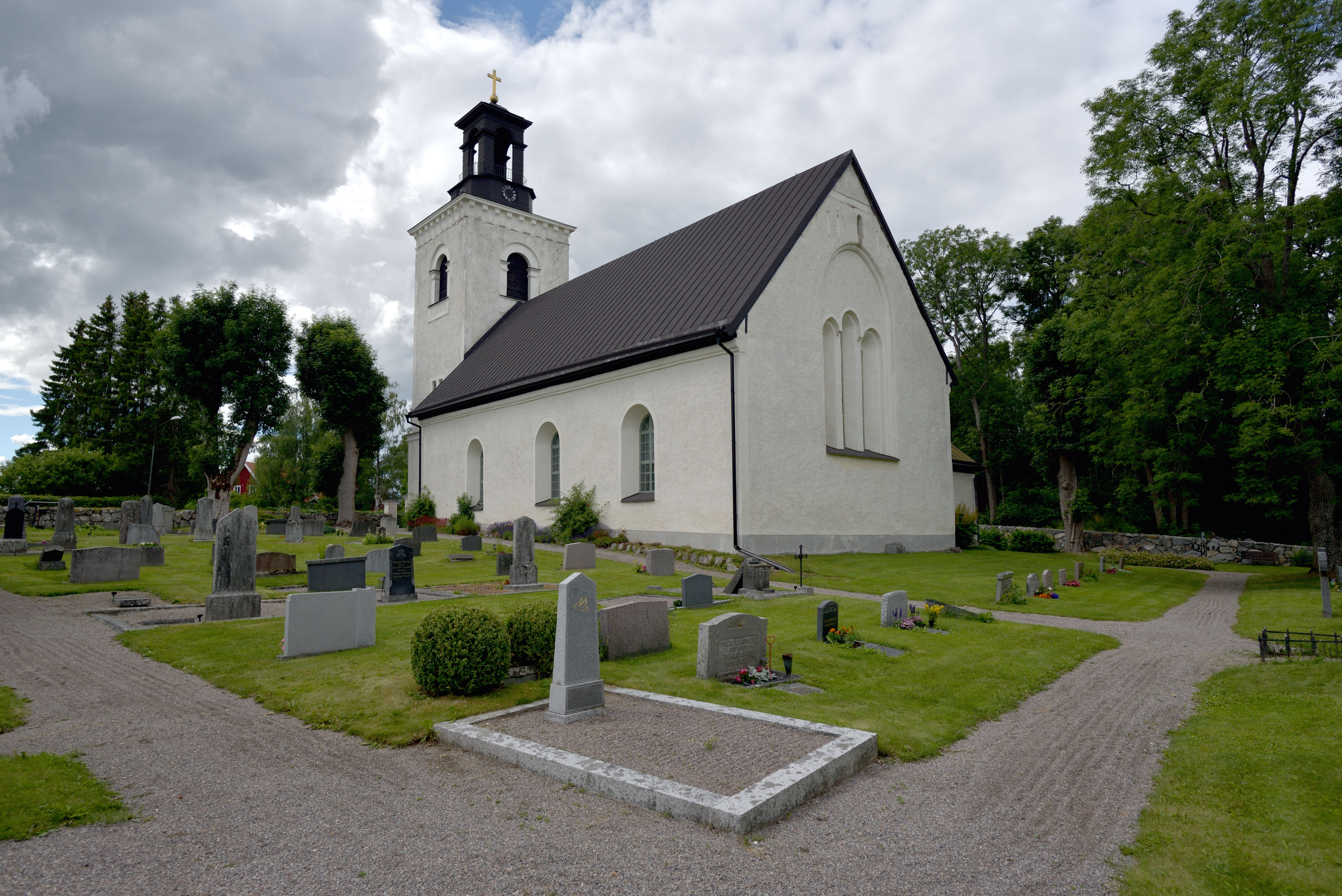 Frösthults kyrka: en vit kyrka med ett torn, omgiven av Frösthults kyrkogård.