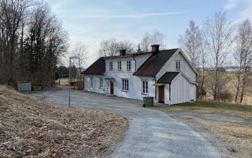 En grusväg leder ner till ett vitt hus.