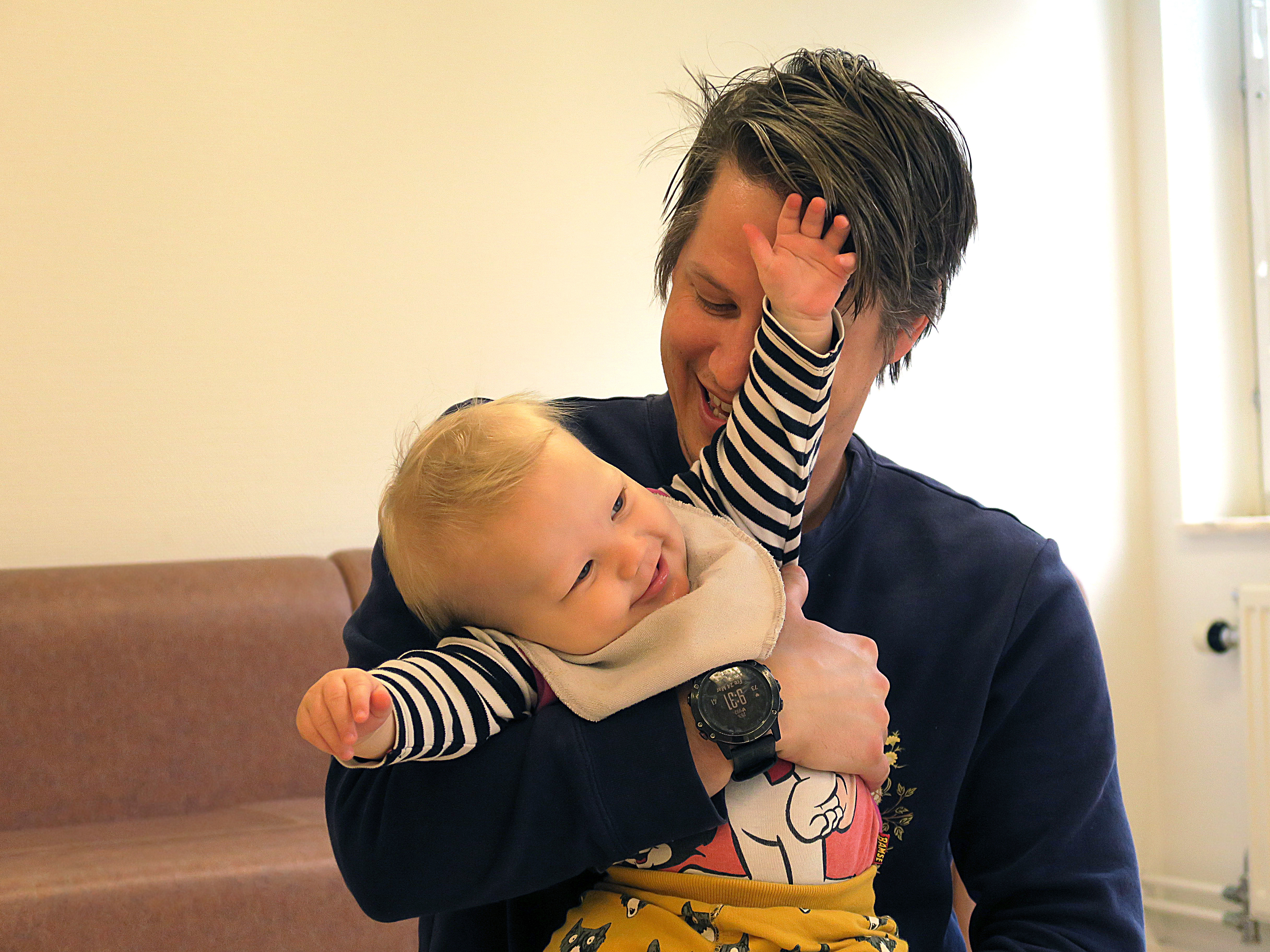 En pappa håller sin sjumånadersbebis i famnen. Barnet busar och försöker ta sig loss.