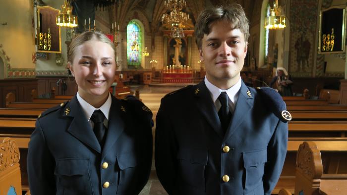 En kvinna och en man i militäruniformer står i en kyrka. De ler mot kameran.