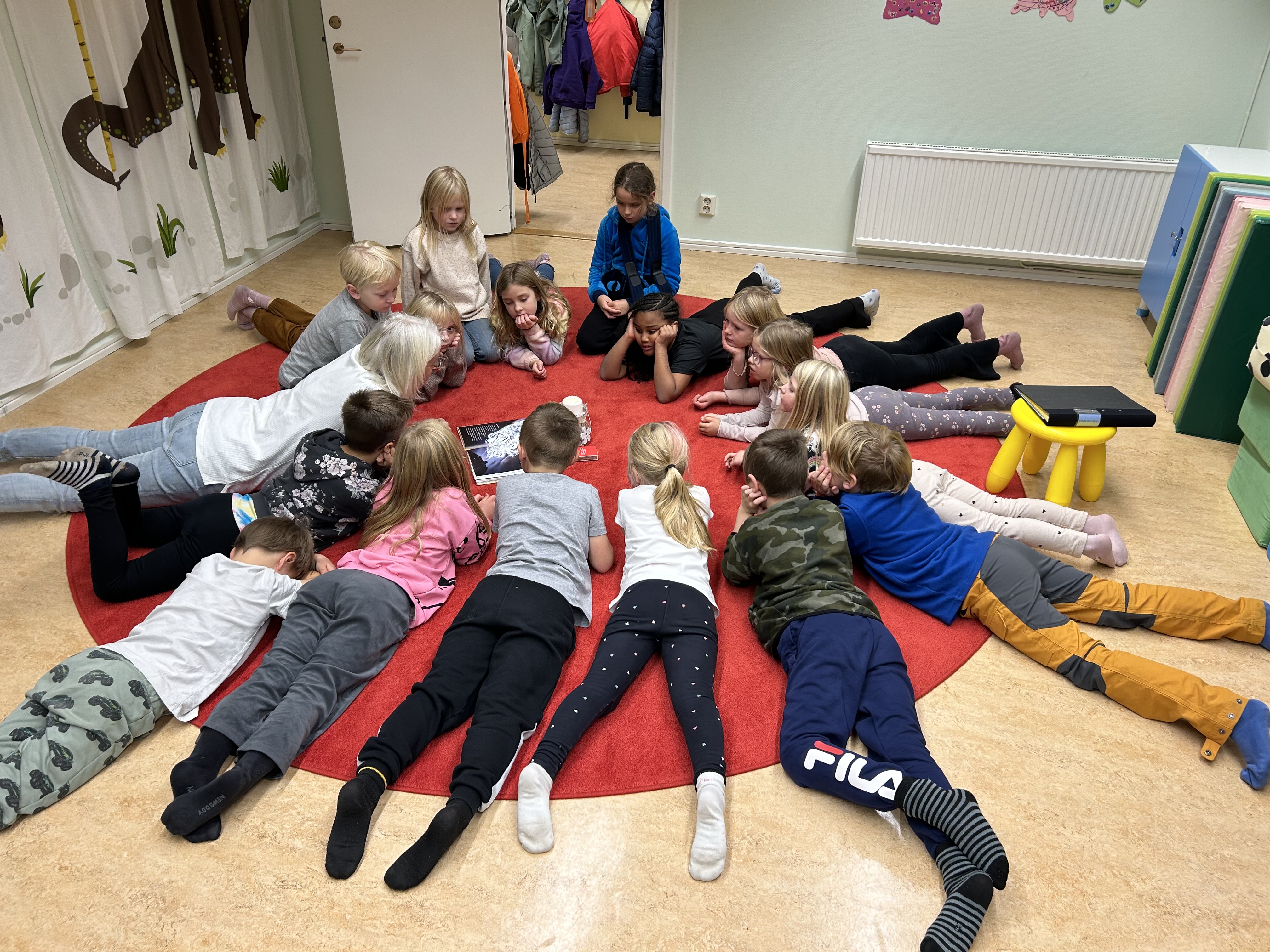 En grupp barn ligger på mage i en cirkel.
