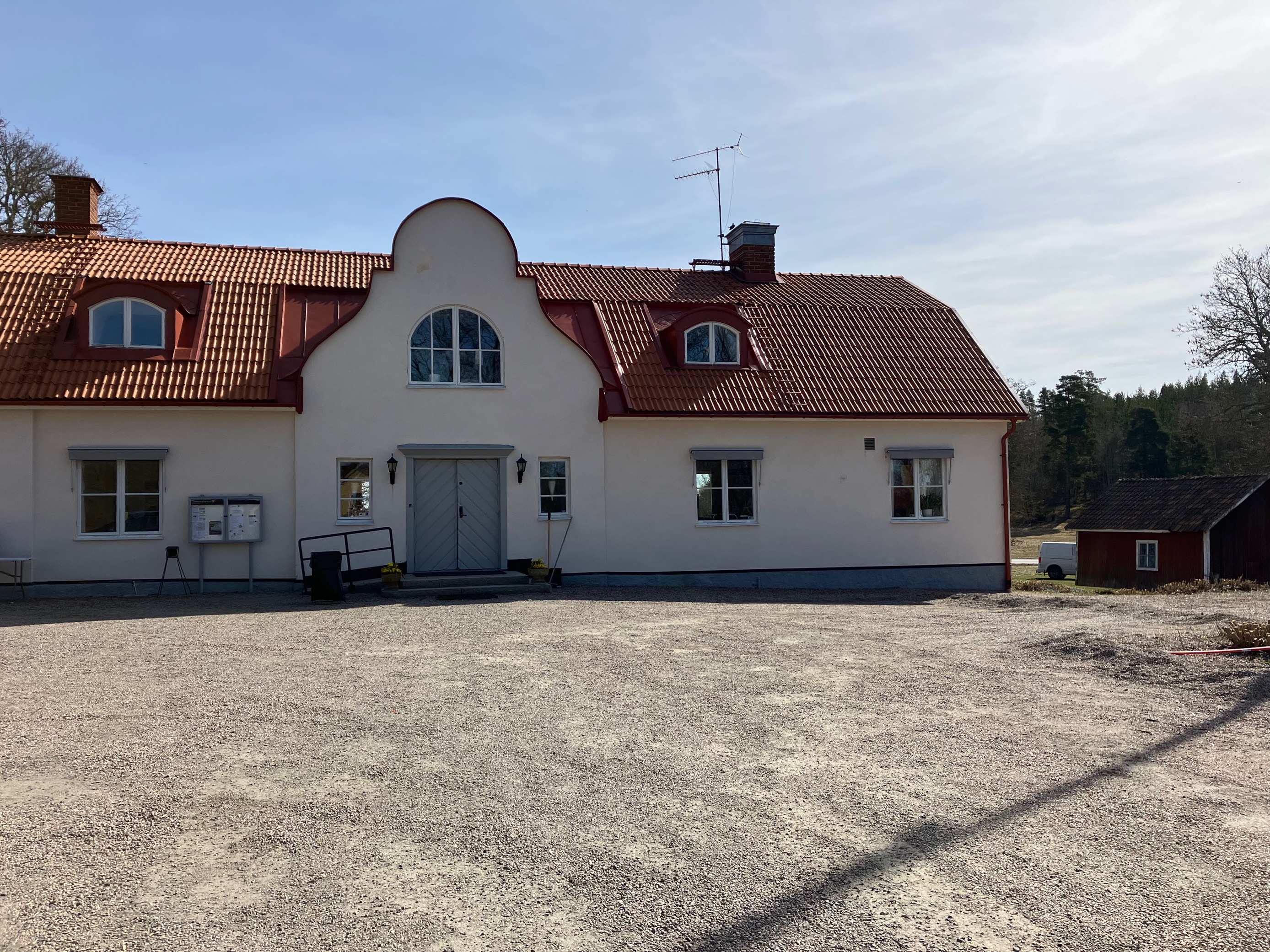 Vitt hus, grusplan framför. Solen skiner.