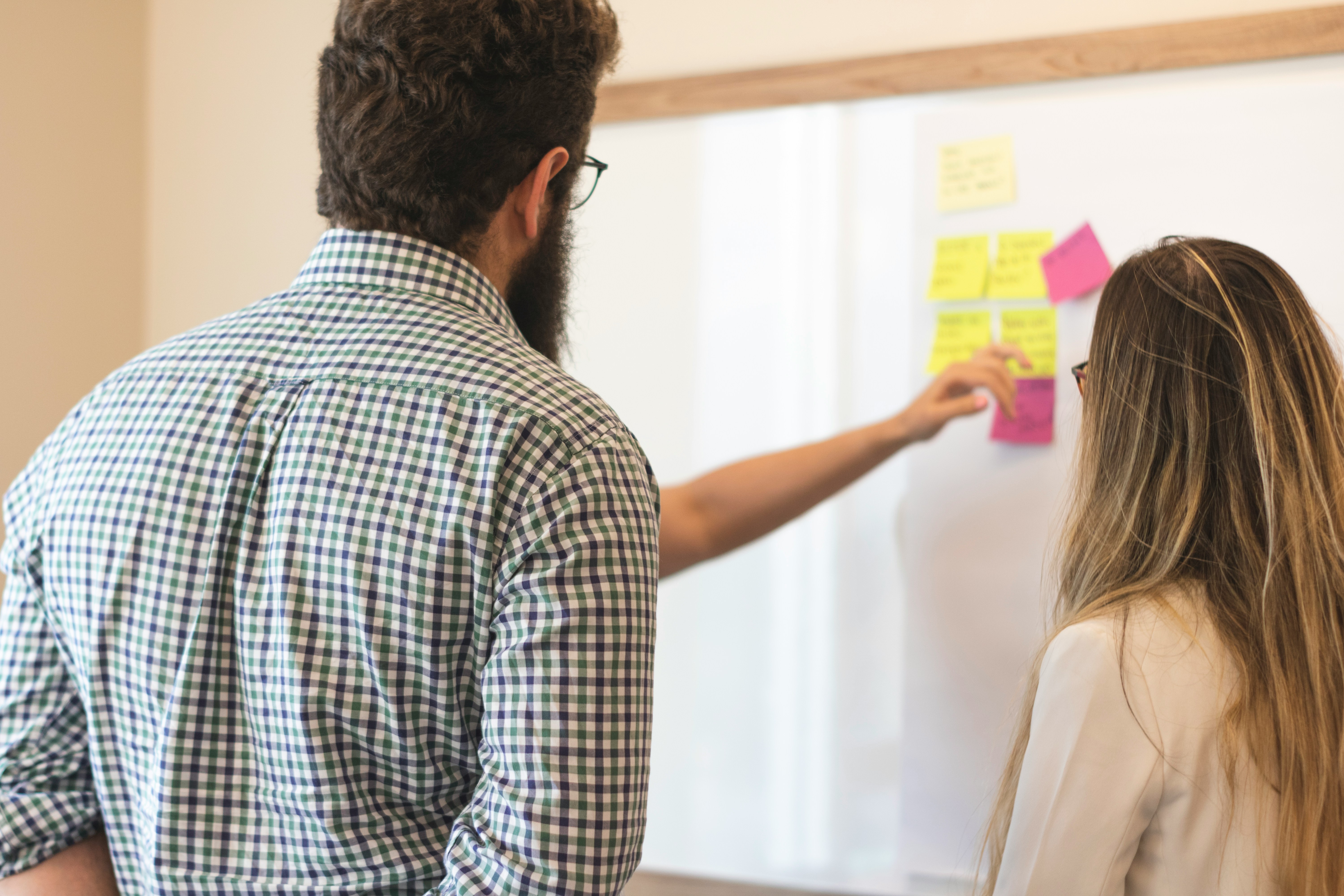 Personen klistrar post-it lappar på en whiteboard.