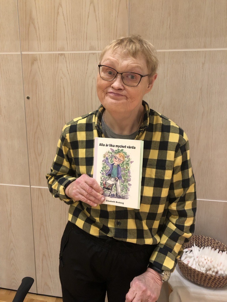 Elisabeth står vid ljusbäraren i Sandared med sin bok