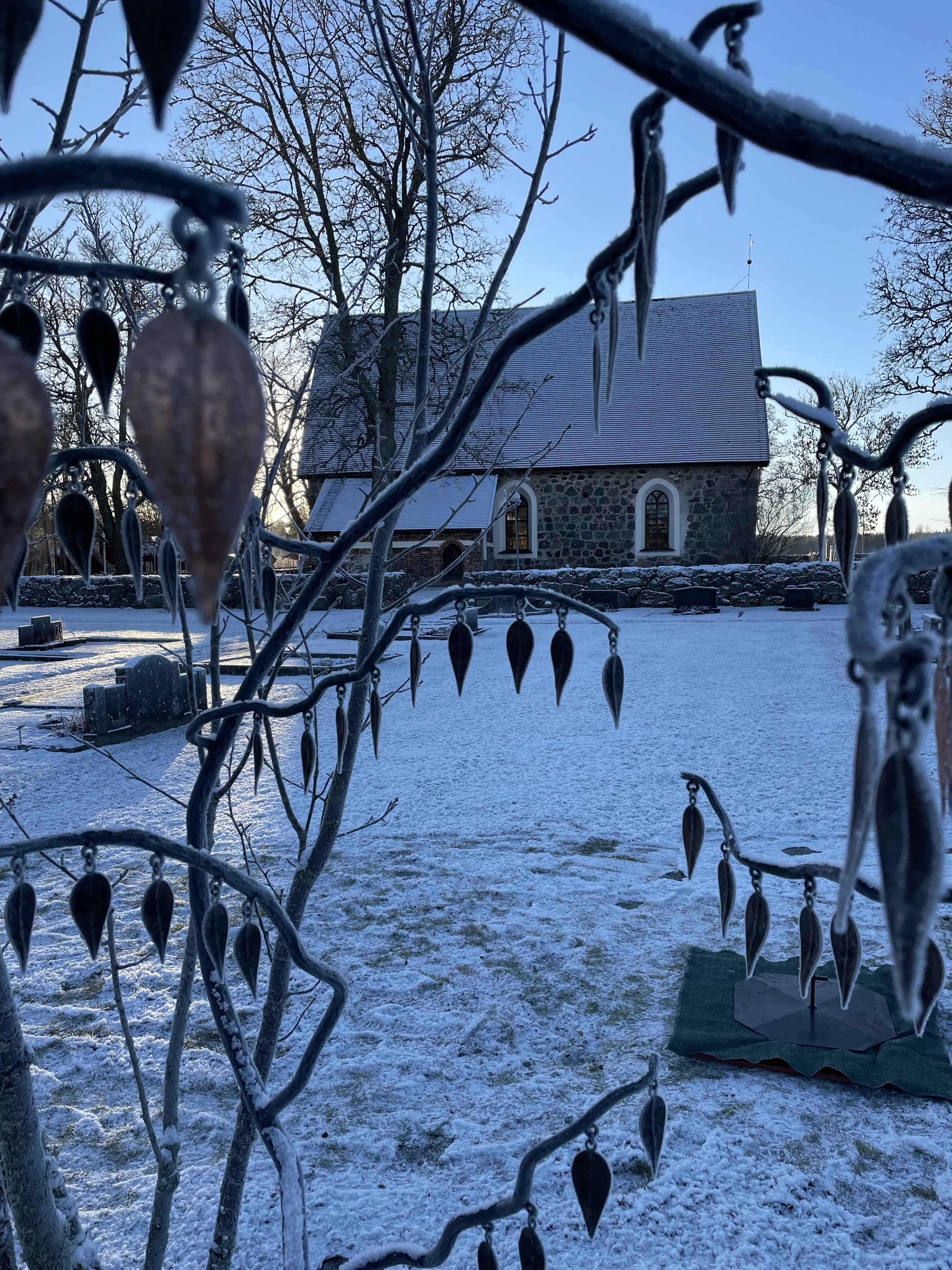 Jumkils kyrka med minnesträd i förgrunden snö