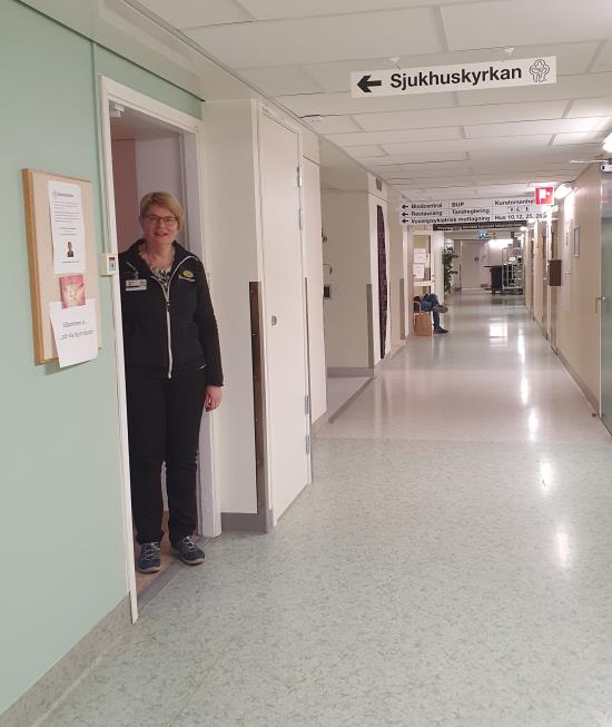 Sjukhusdiakon står i dörren in till Sjukhuskyrkan vy från korridoren 