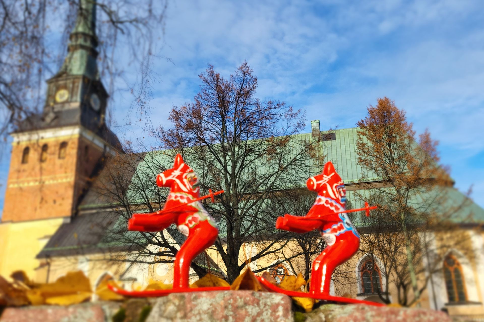 Dalahästar åker skidor framför Mora kyrka