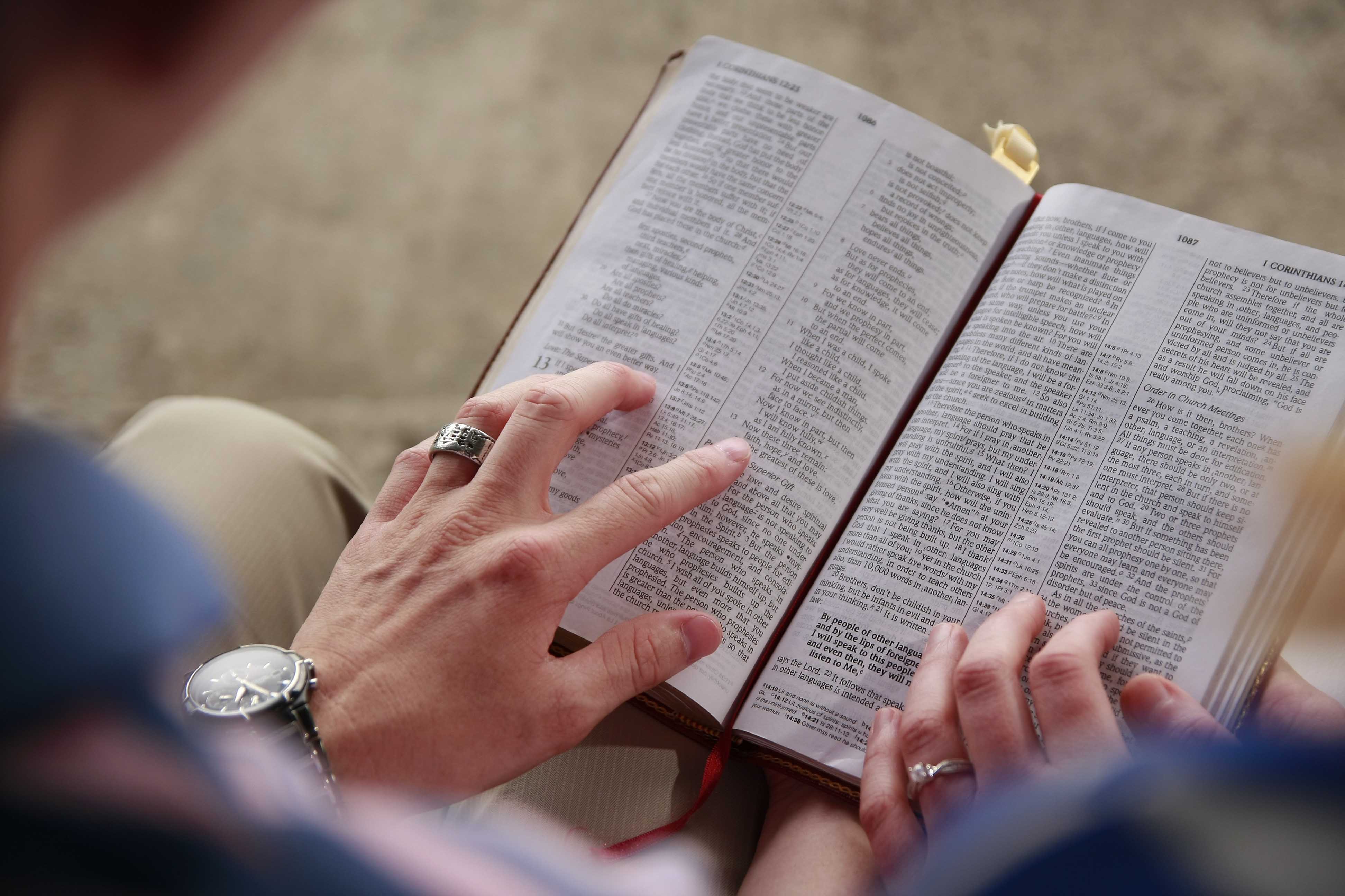 Uppslagen Bibel och två händer