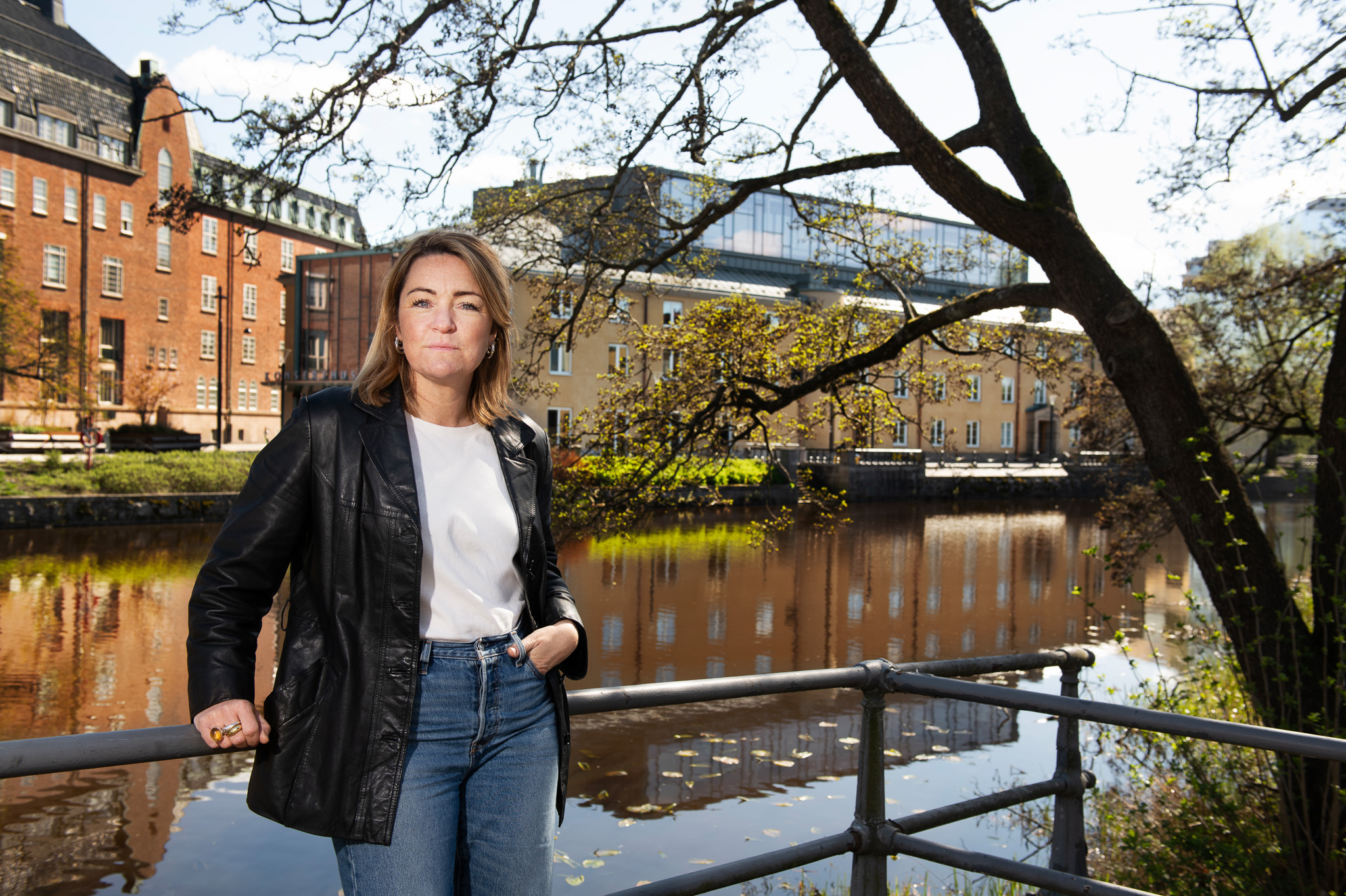 Kvinna står vid en å framför ett stort konserthus.