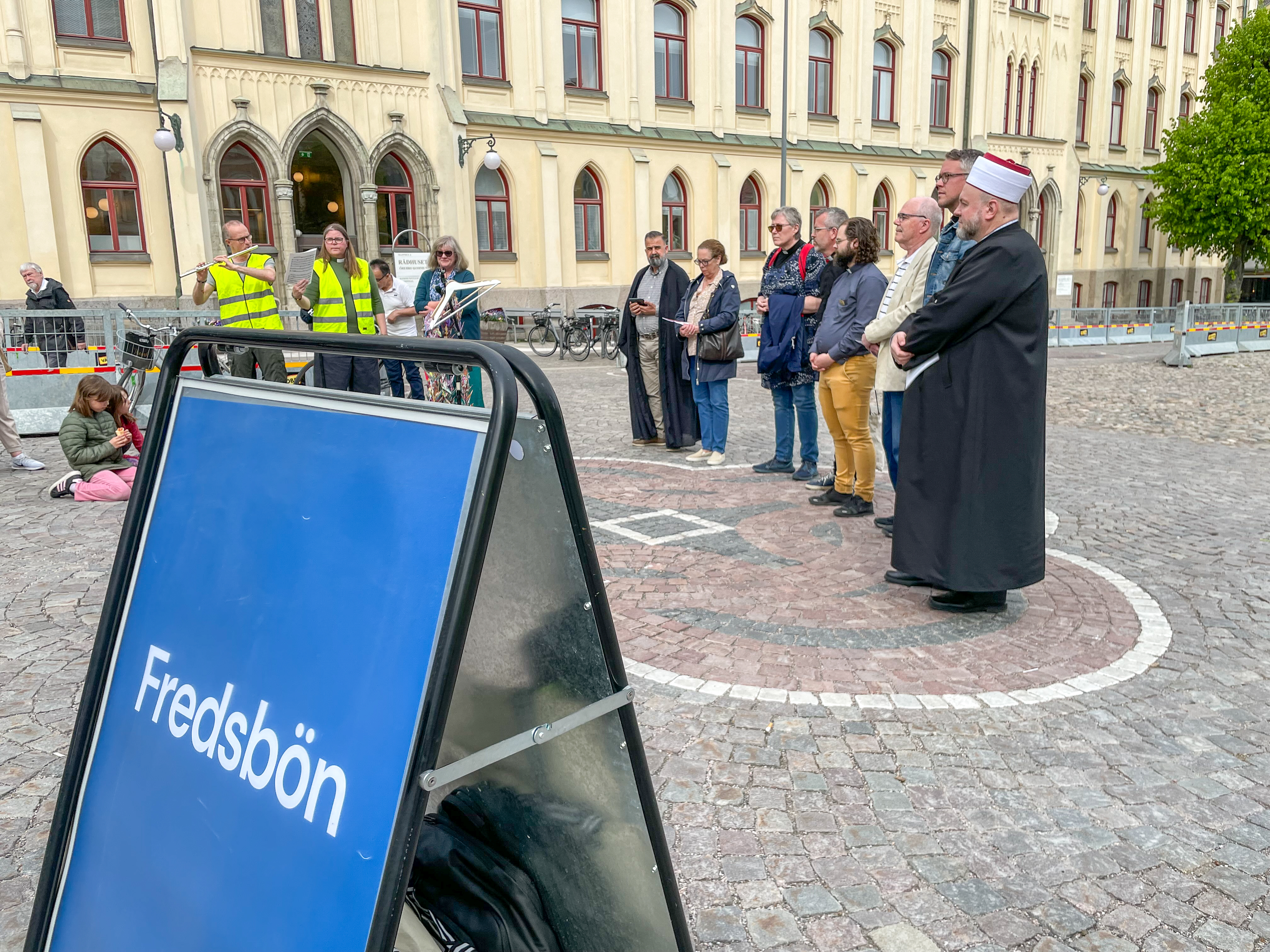 Personer står på ett torg och ber.