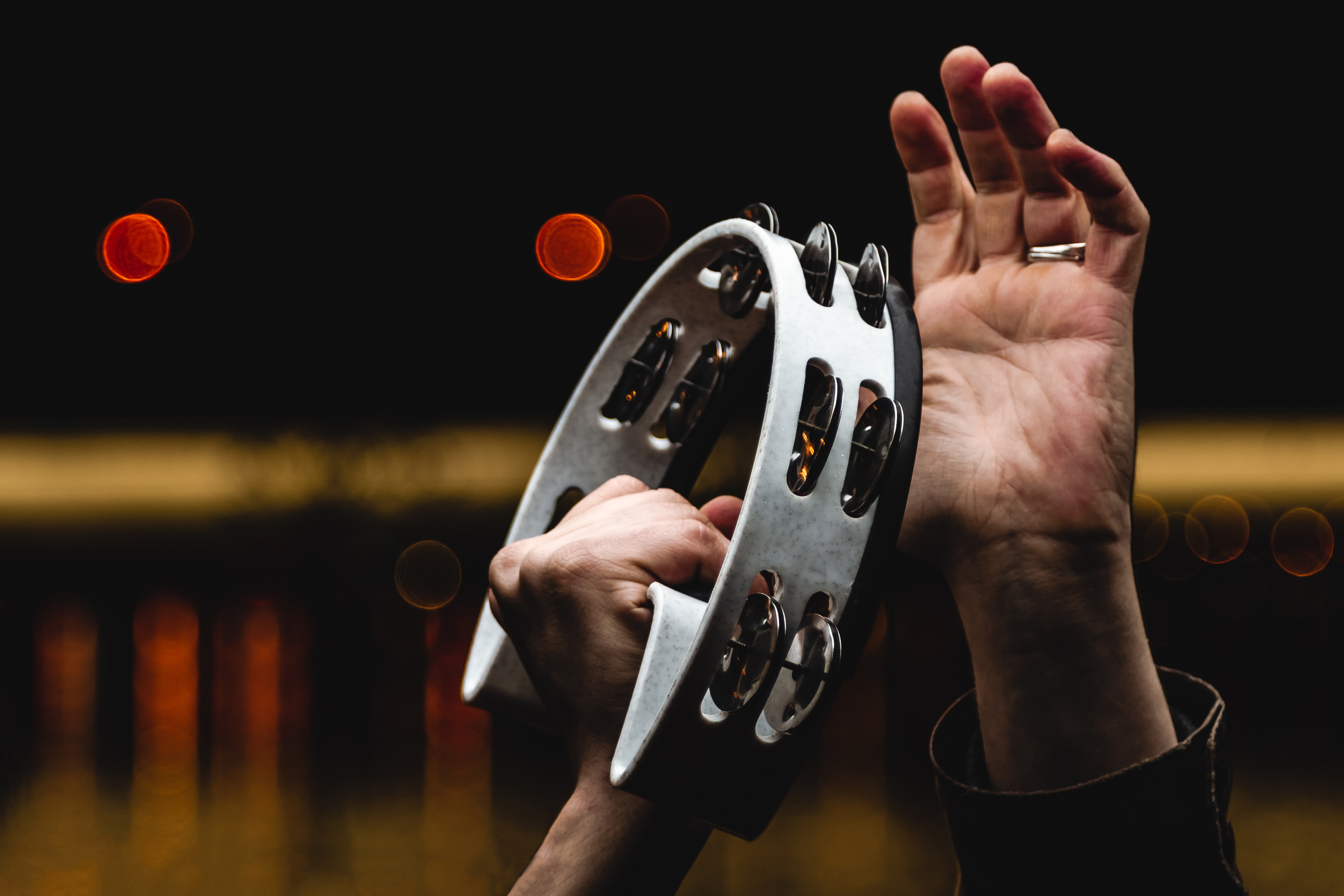 Närbild av händer som spelar på en vit tamburin i en konsert