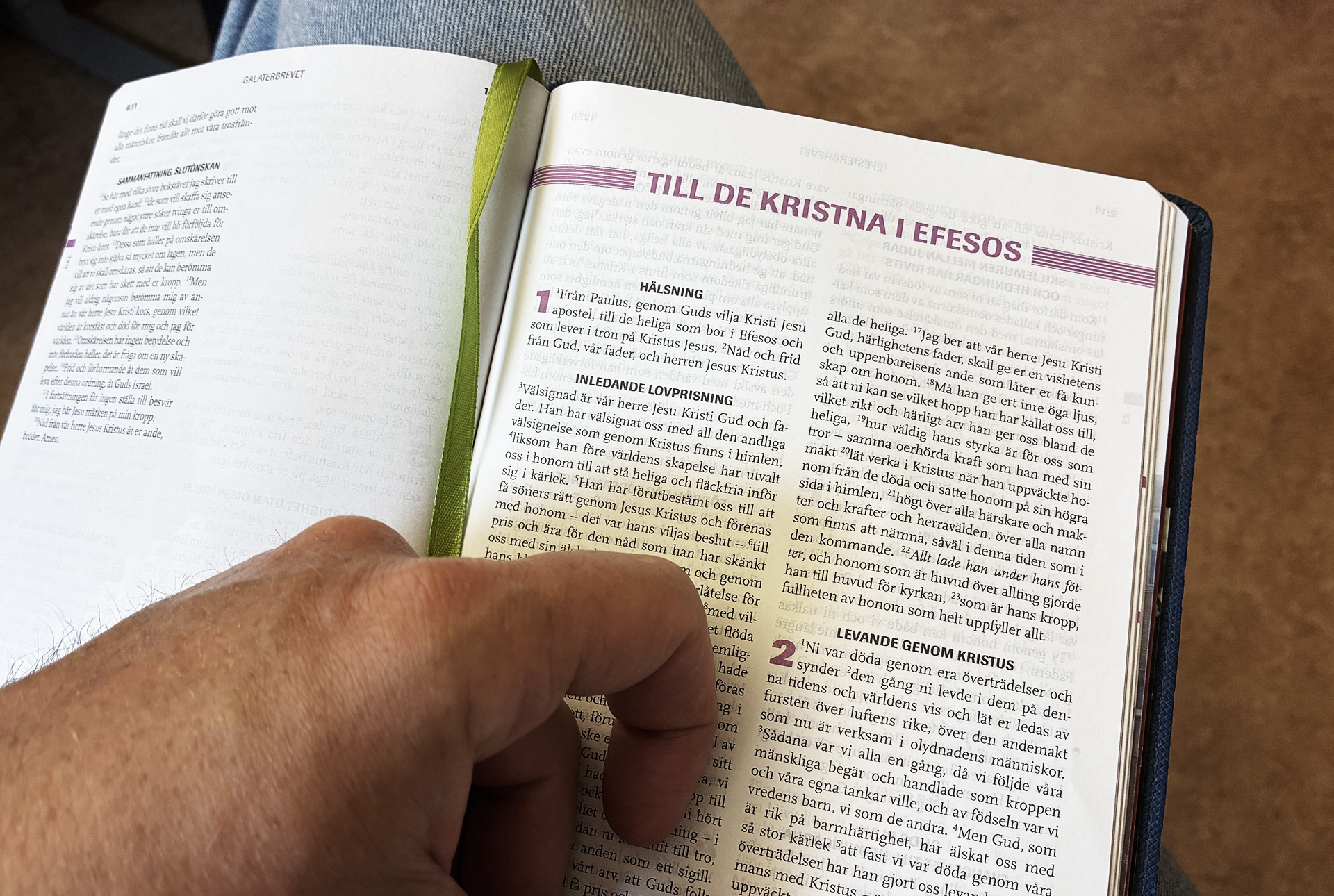 En uppslagen bibel och en hand som följer texten.