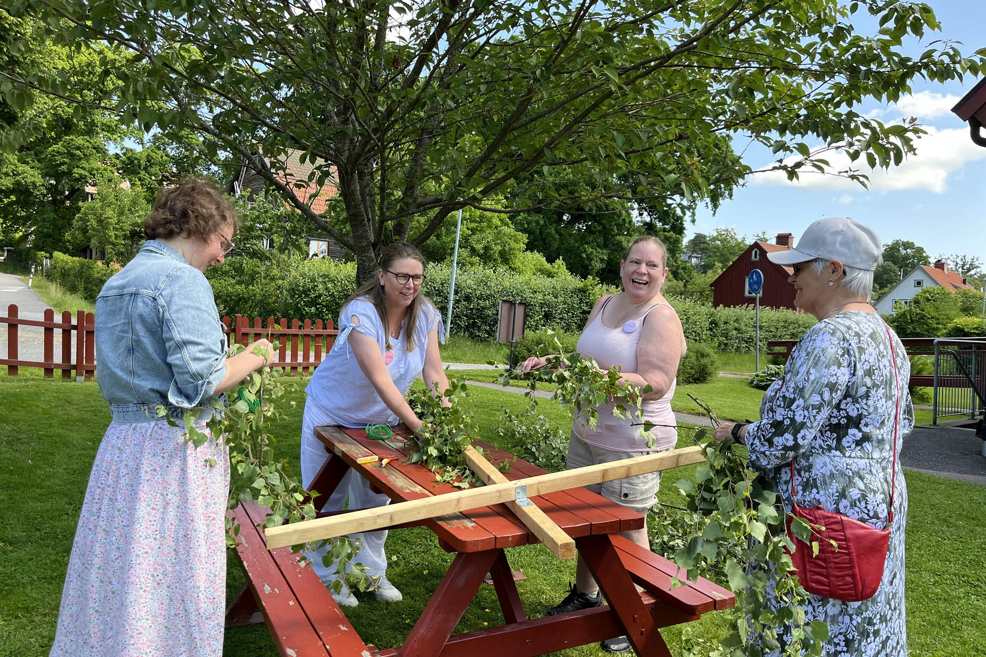 Fyra kvinnor klär en midsommarstång