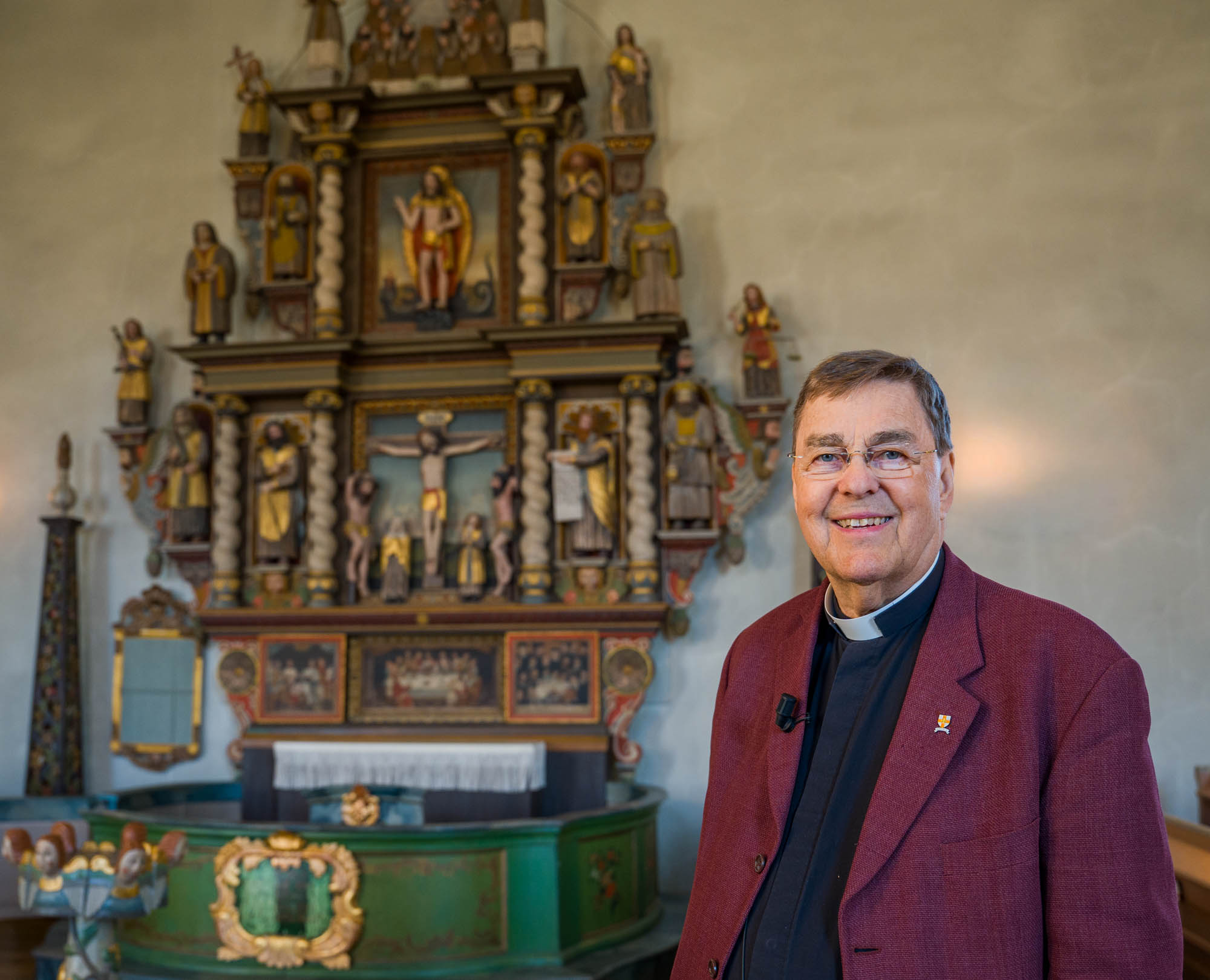 En präst står framför en altaruppsats i Sunne kyrka
