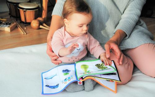 Litet barn bläddrar i en bok med stöd av mamma