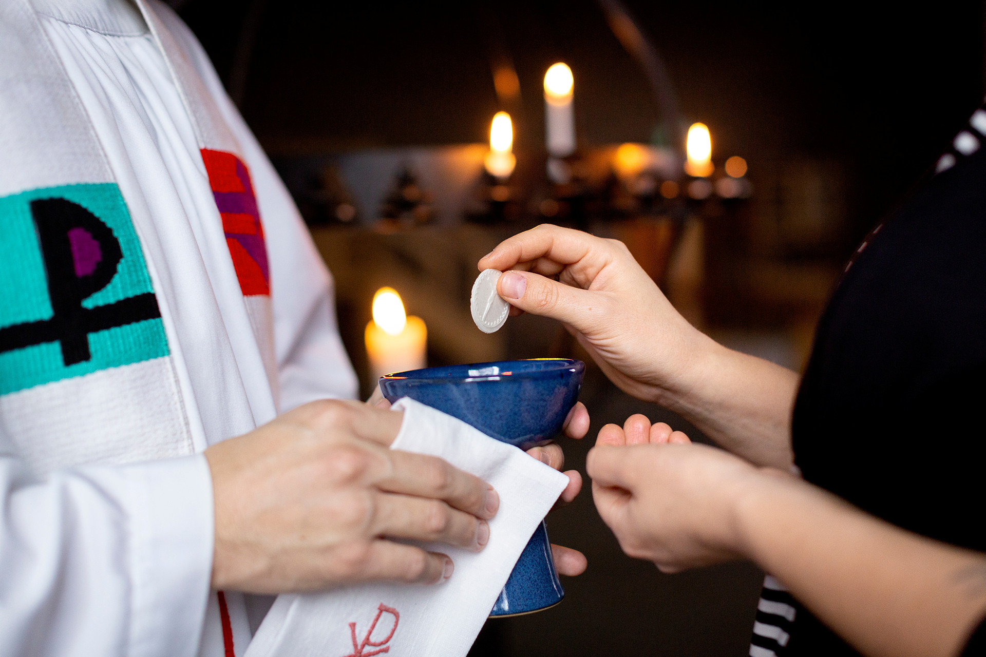 Gudstjänst med nattvard. Närbild på händer som tar emot nattvarden av präst.