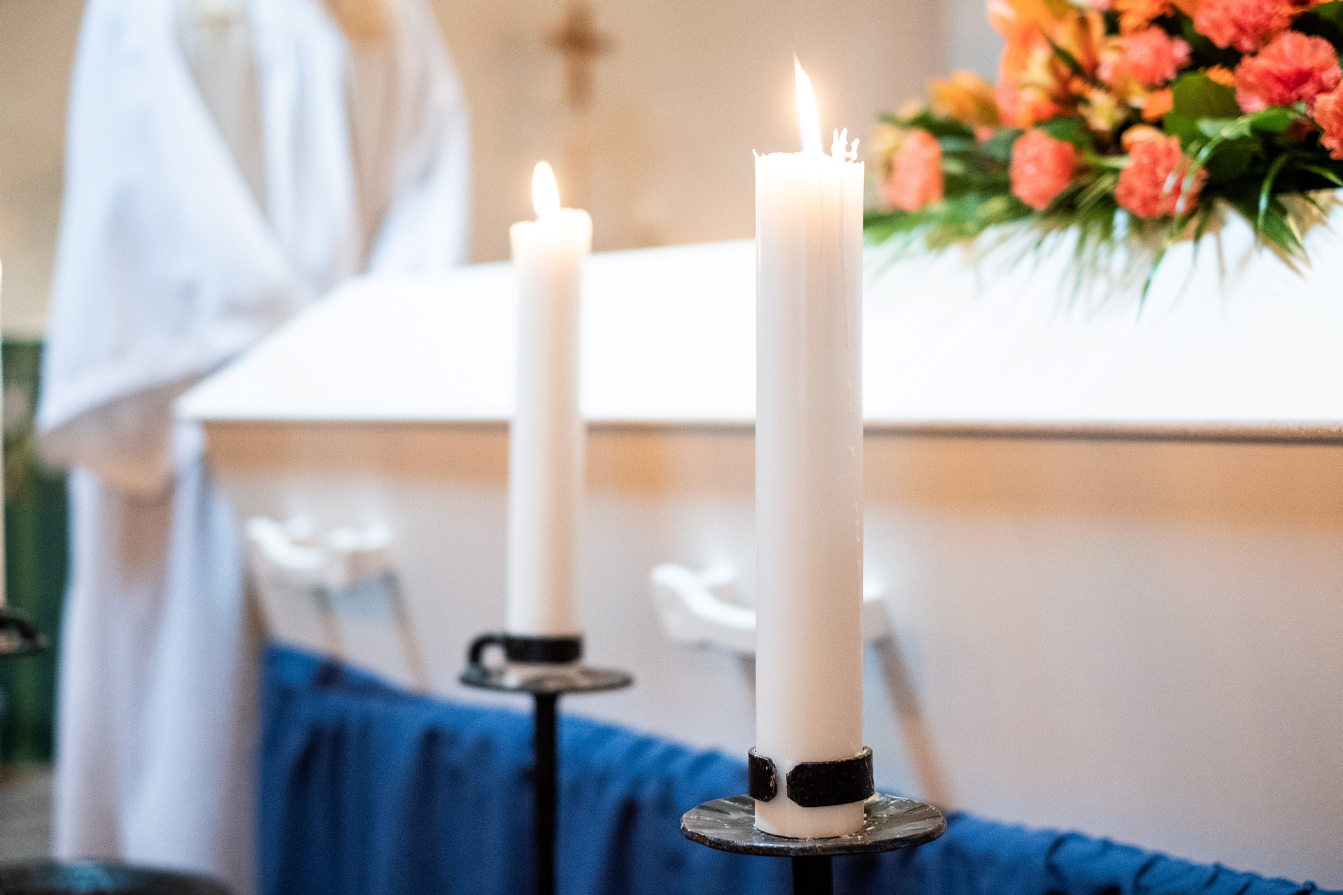 Vit kista med rosor som kistdekoration och två brinnande ljus