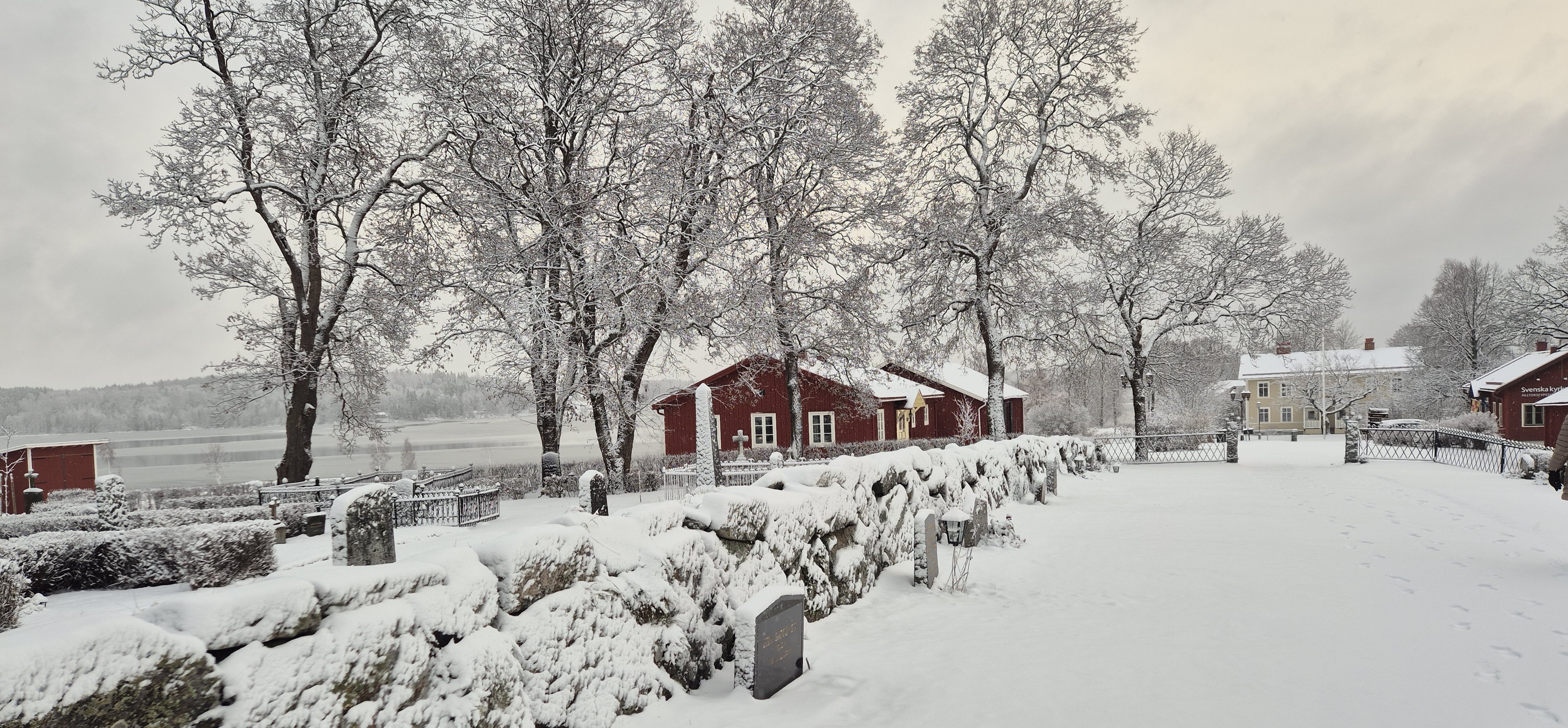 Bild på röd byggnad och bakgrunden en sjö. Det är vinter och snö.