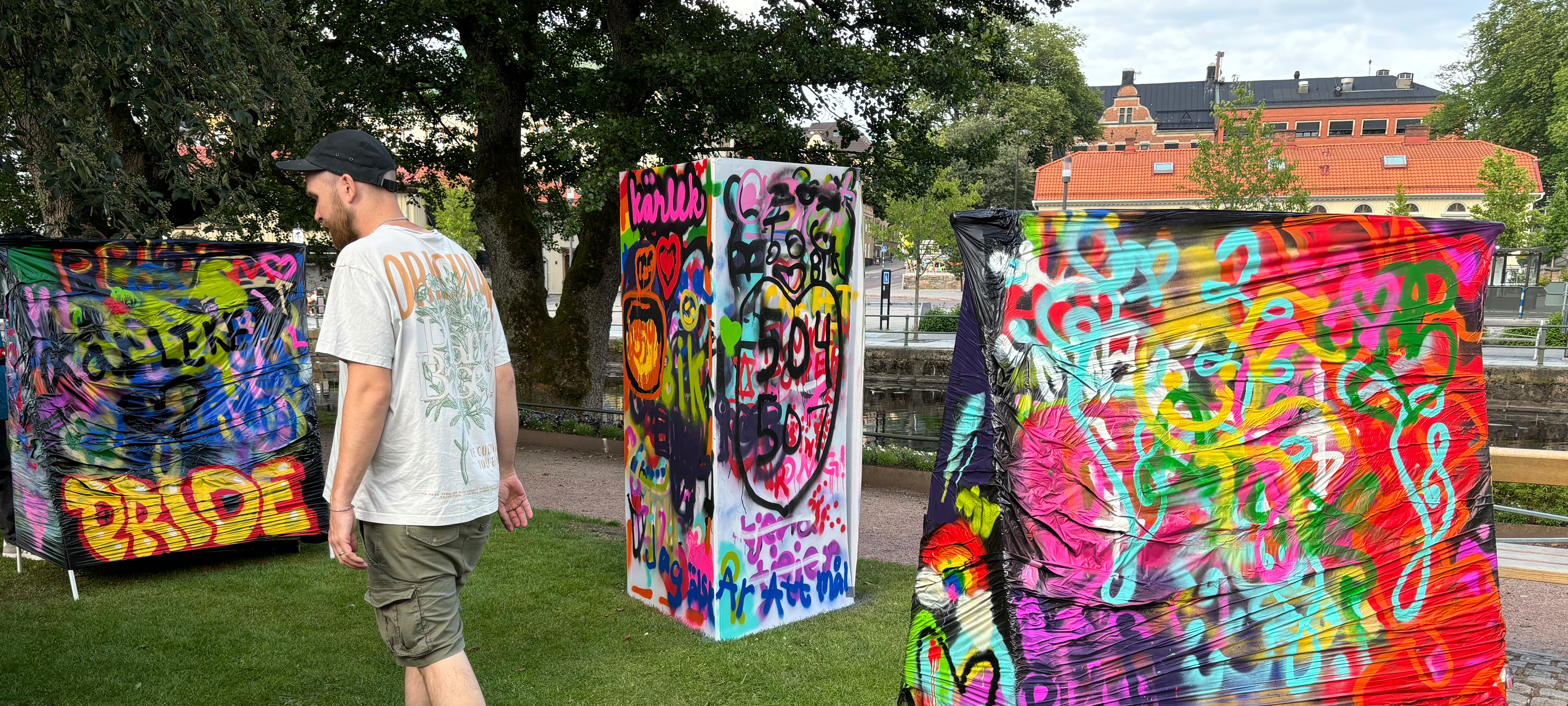 Graffiti på uppspända skärmar i parkmiljö.