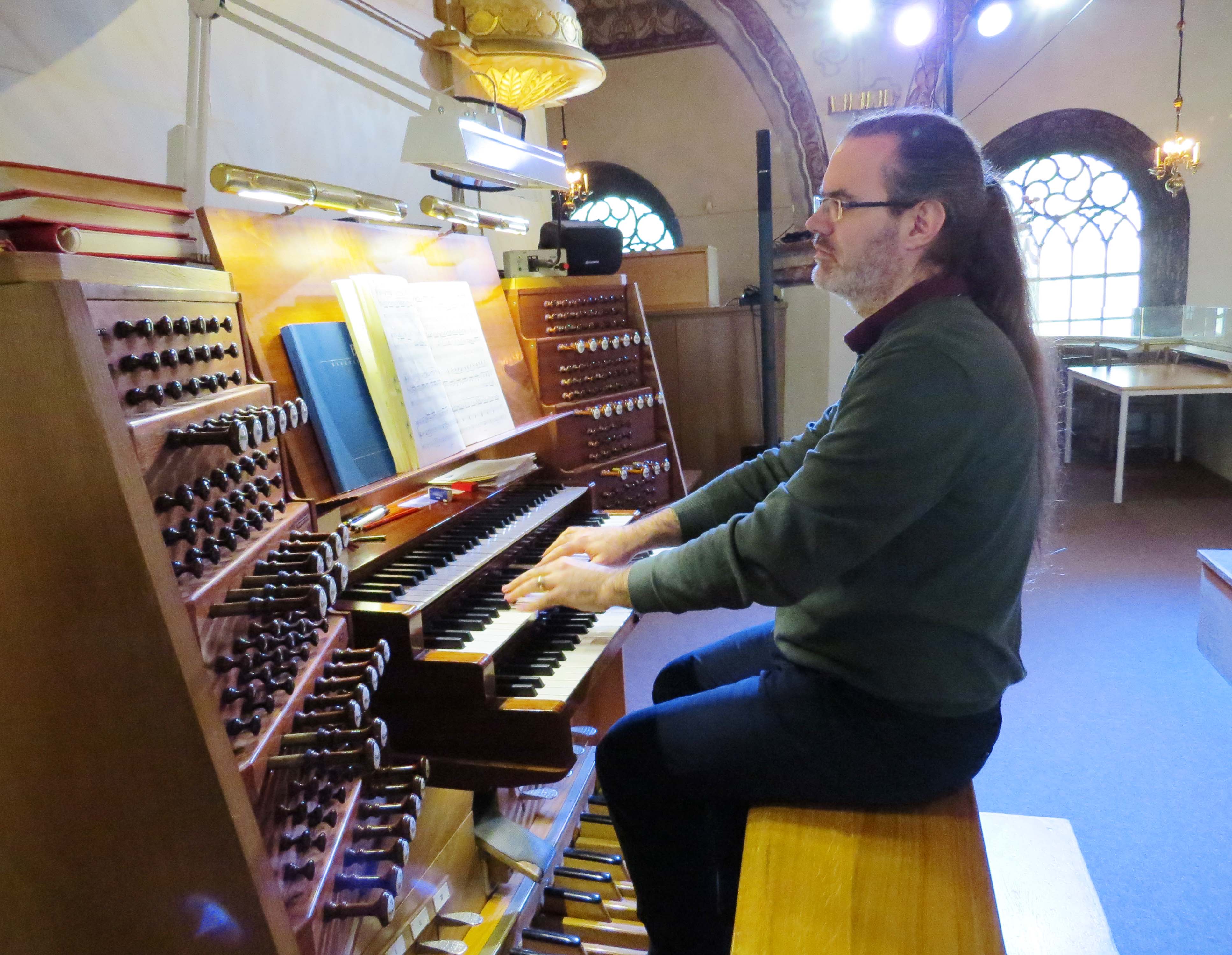 Man sitter och spelar på kyrkorgel.