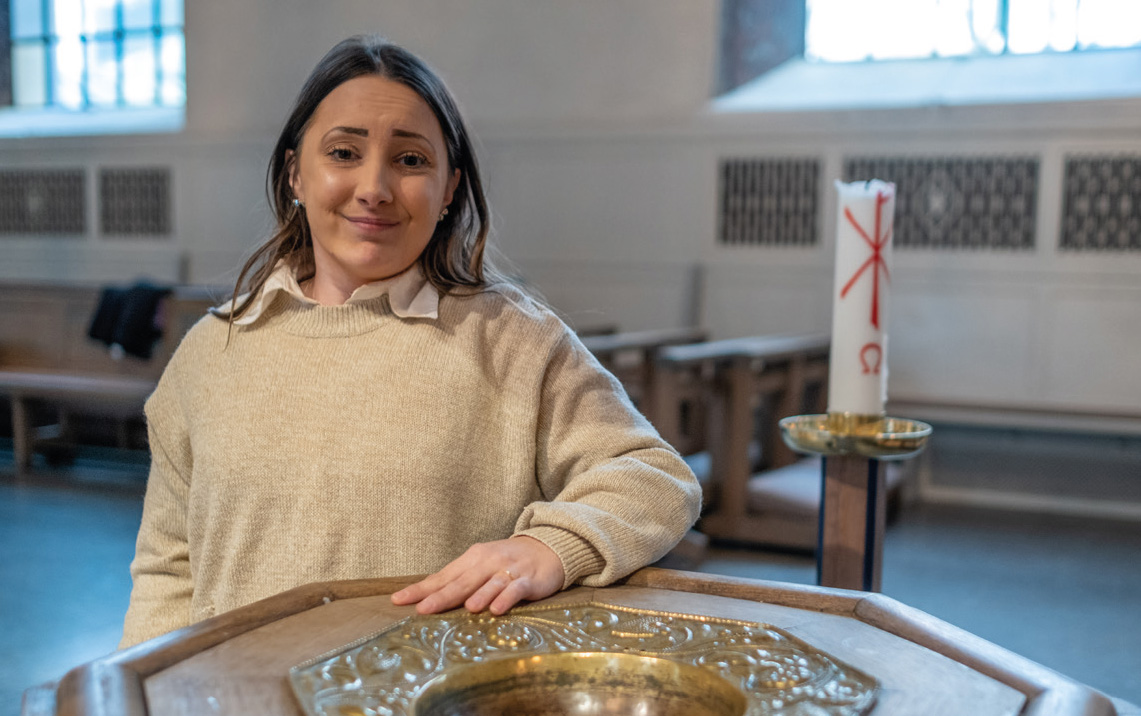 Kvinna vid dopfunt i kyrka.