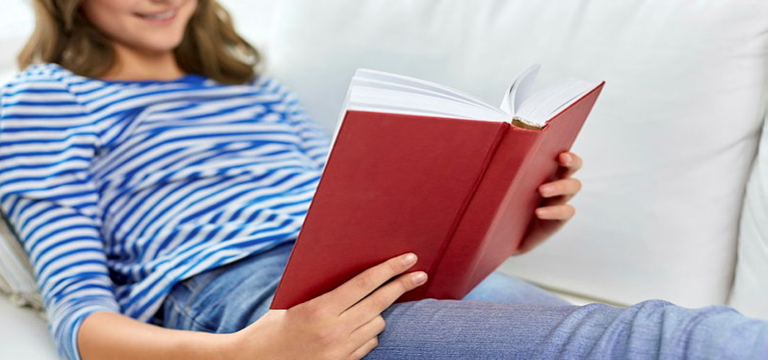 En person ligger skönt tillbakalutad i soffan och läser en bok