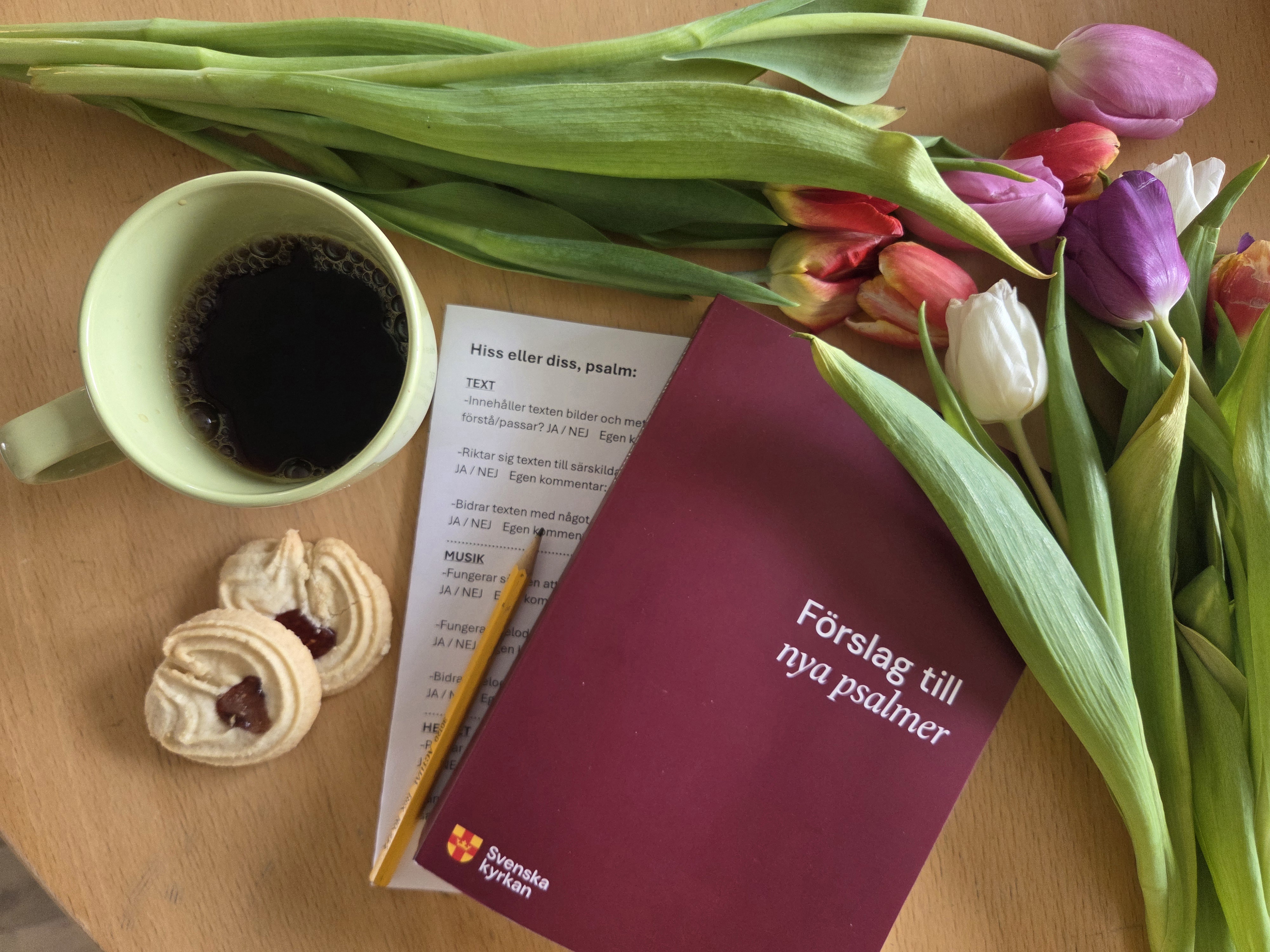 Psalmboken med blommor och kaffe intill.