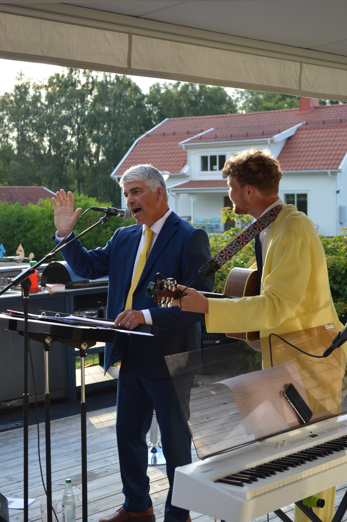 Två personer står utomhus och spelar gitarr och sjunger.
