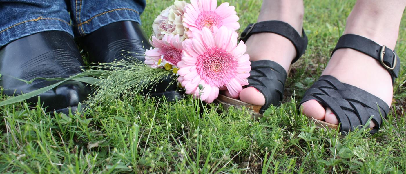 bröllopsfoto på grova skor och träskor i sandalmodell, med en rosa liten brudbukett mellan