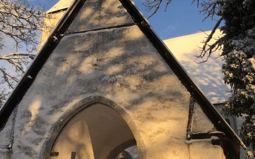 Stigluckan vid Rute kyrka. Snön ligger djup. Solen lyser varmt. 