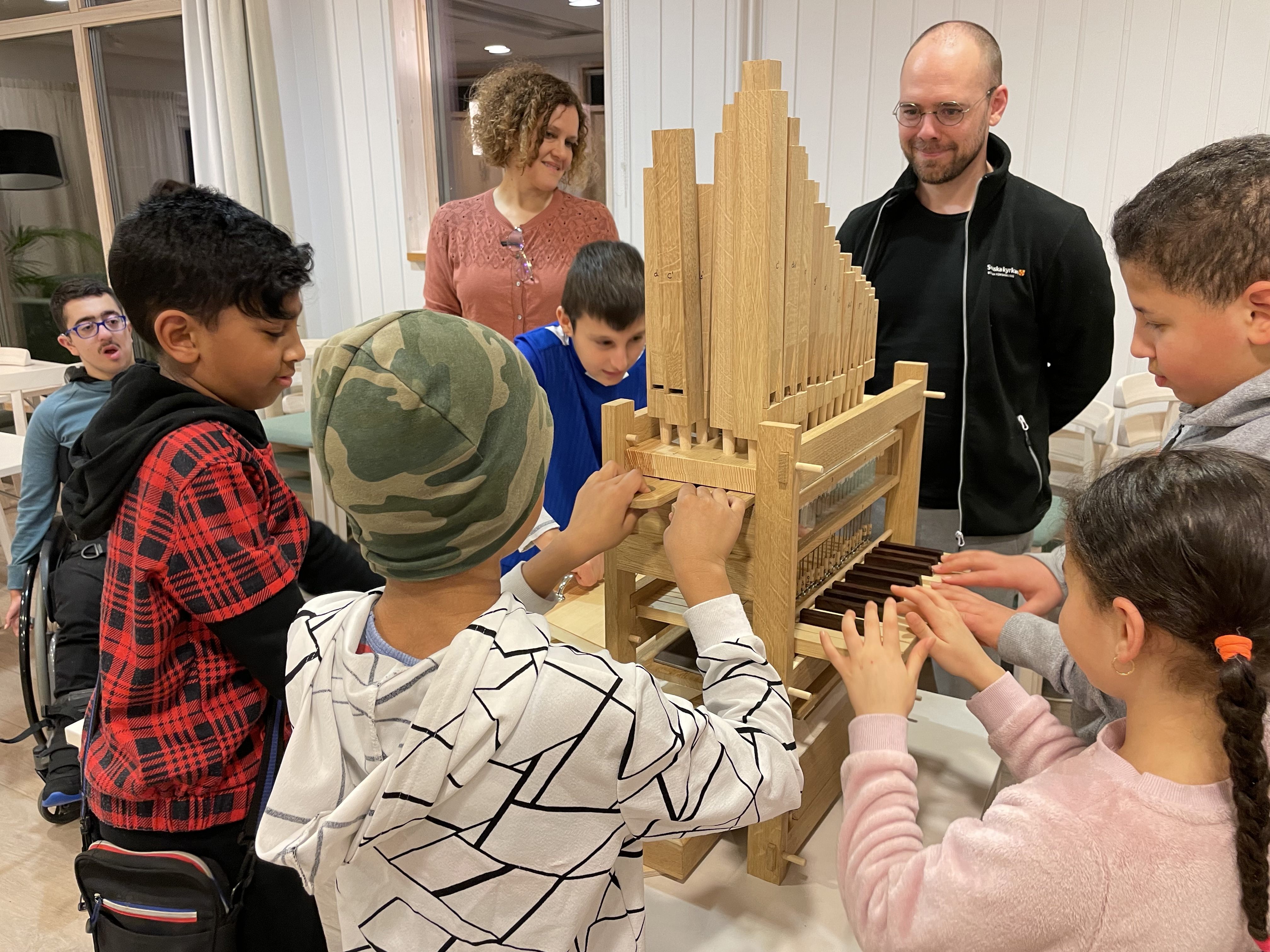 Sex barn är samlade runt den lilla, men fullt fungerande träorgeln