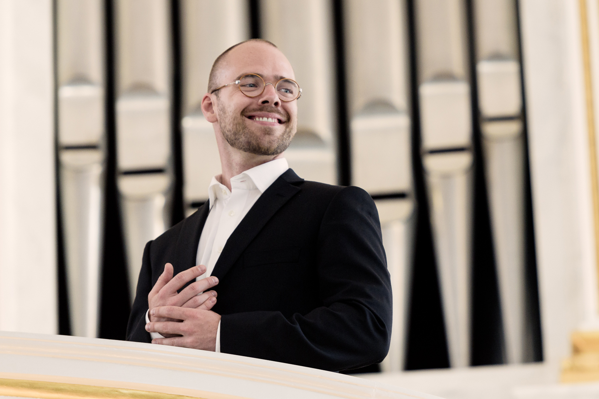 Kyrkomusiker Anton Högberg på orgelläktare framför orgelpipor.
