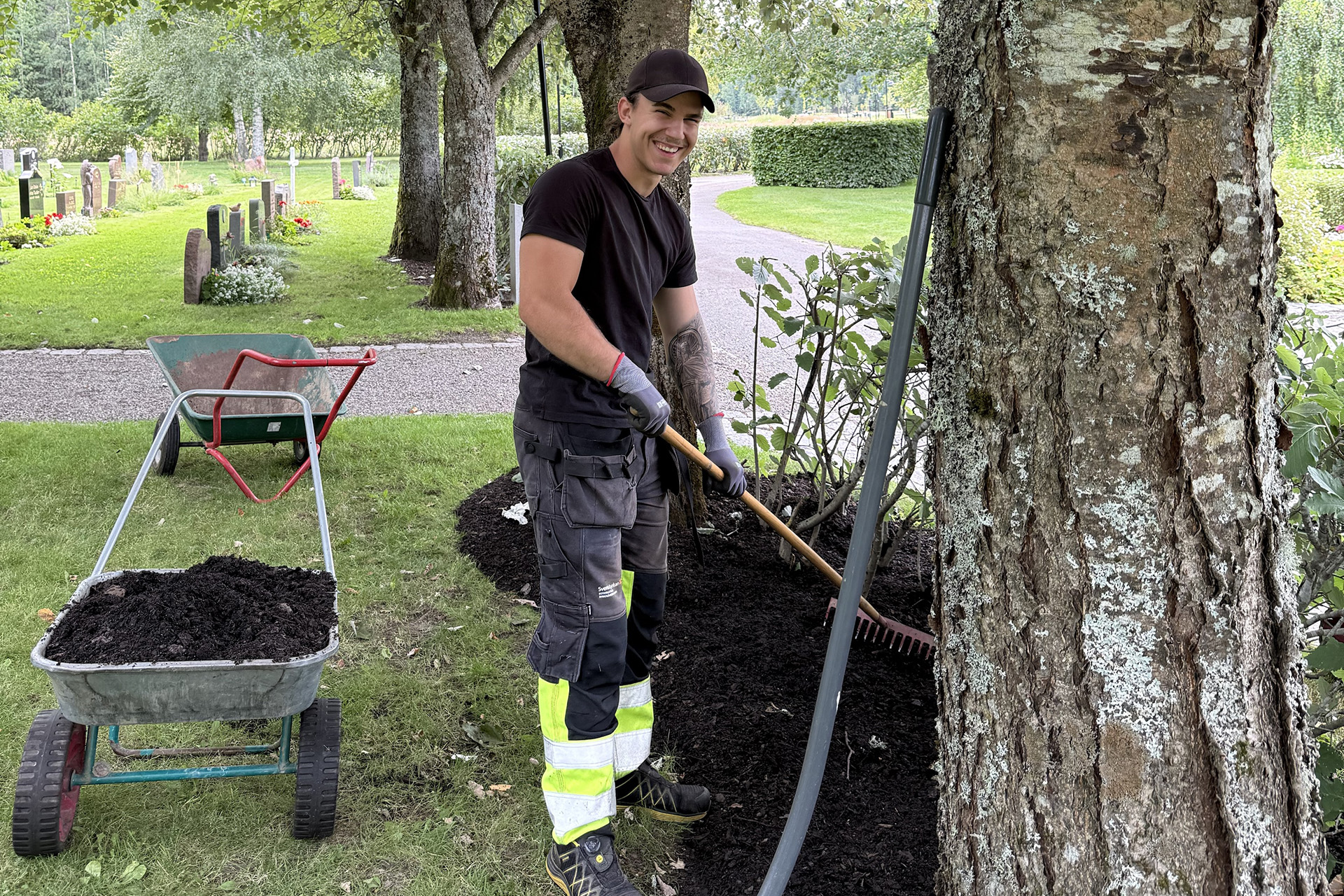 Sommajobbare Luca krattar i rabatt på Lilla Dalens begravningsplats.