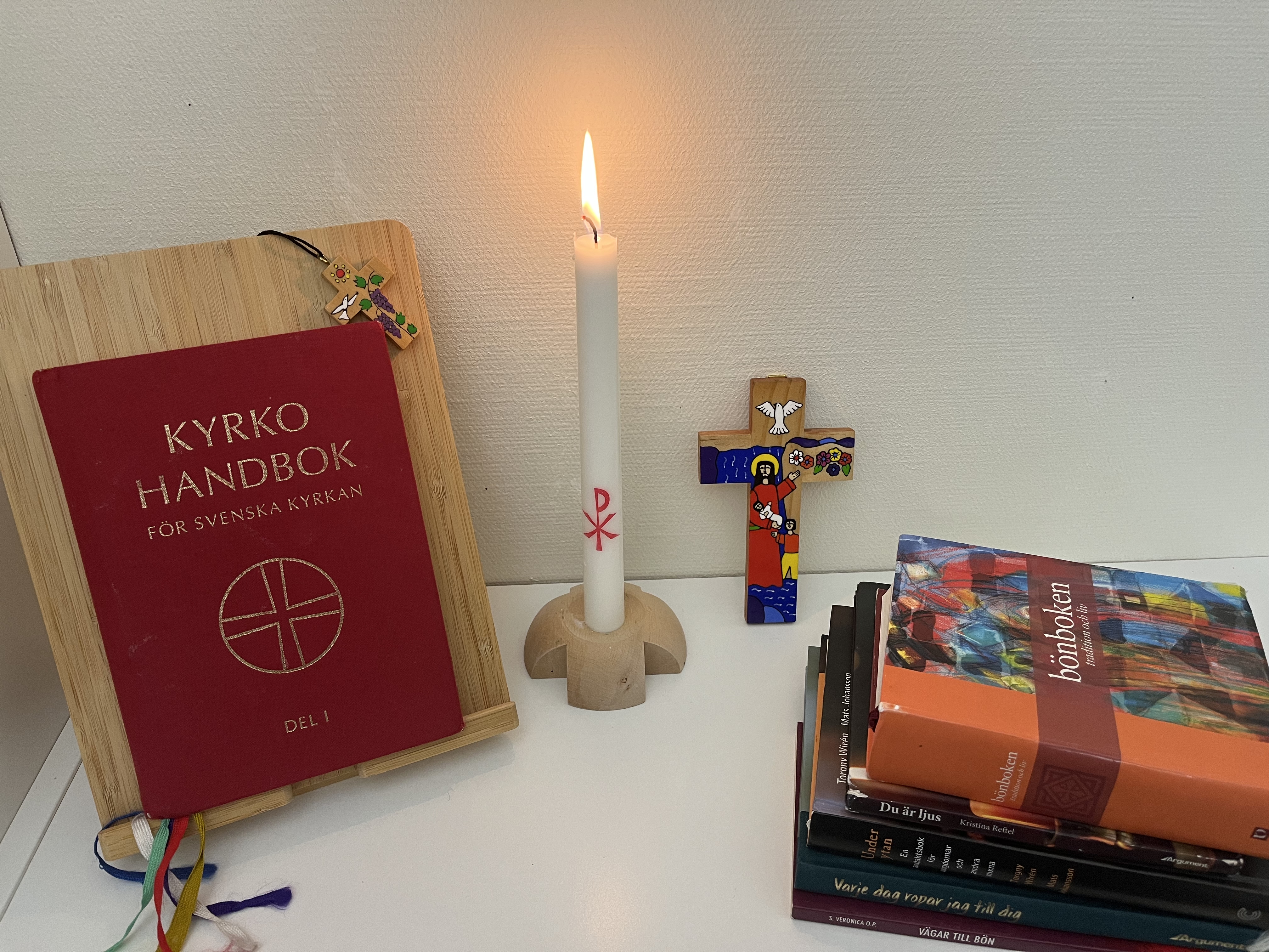 Bibel, psalmbok, kors och ett tänt ljus.