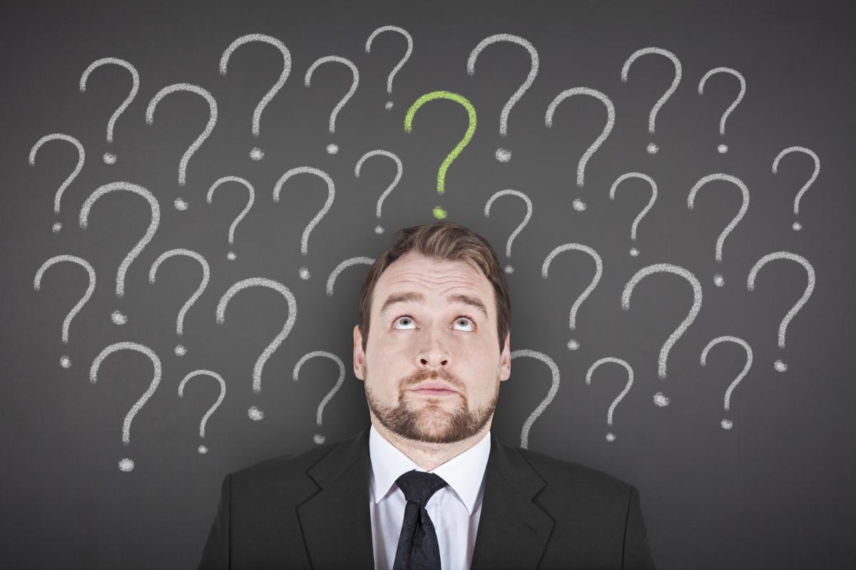 En man står lutad mot en vägg med en massa frågetecken på.