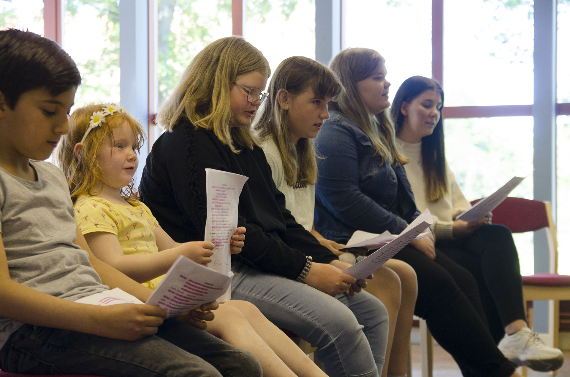 6 barn i olika åldrar sitter och över på sånger.
