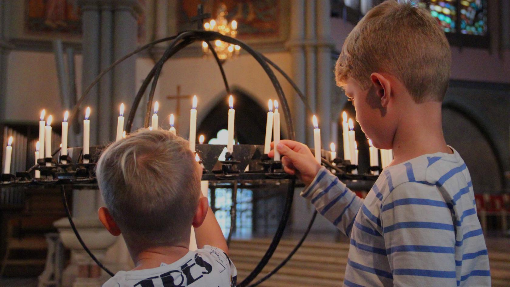 Två barn sätter ljus i ljusbäraren i Oscar Fredriks kyrka.