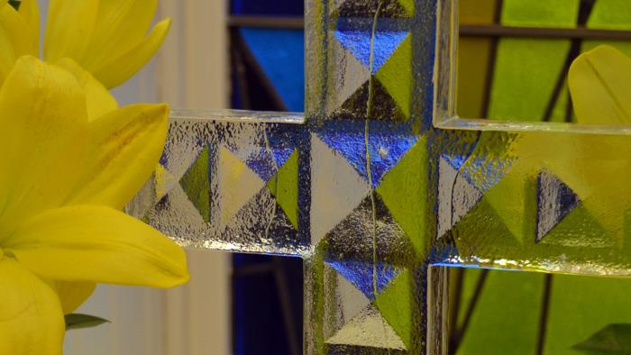 Detaljbild på ett glaskors med påskliljor.