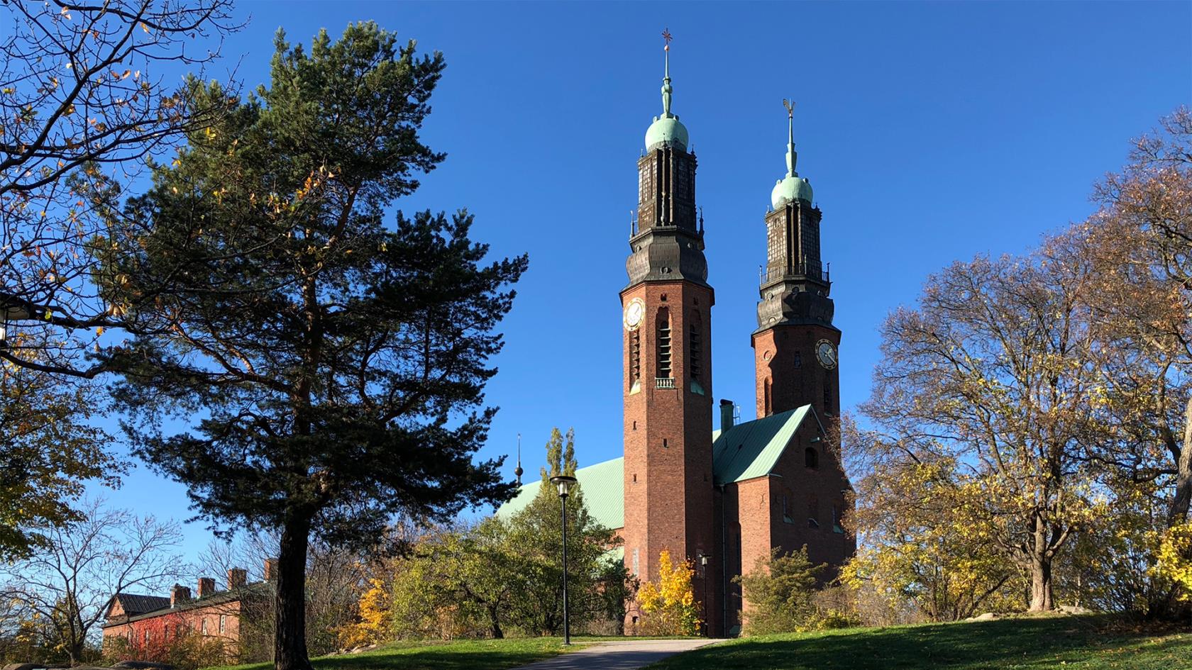 Högalidskyrkan med sina två torn, blå himmel och träd. Det ser ut att vara höst. 