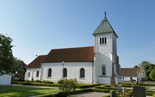 Vit kyrka med torn och rött tegeltak.