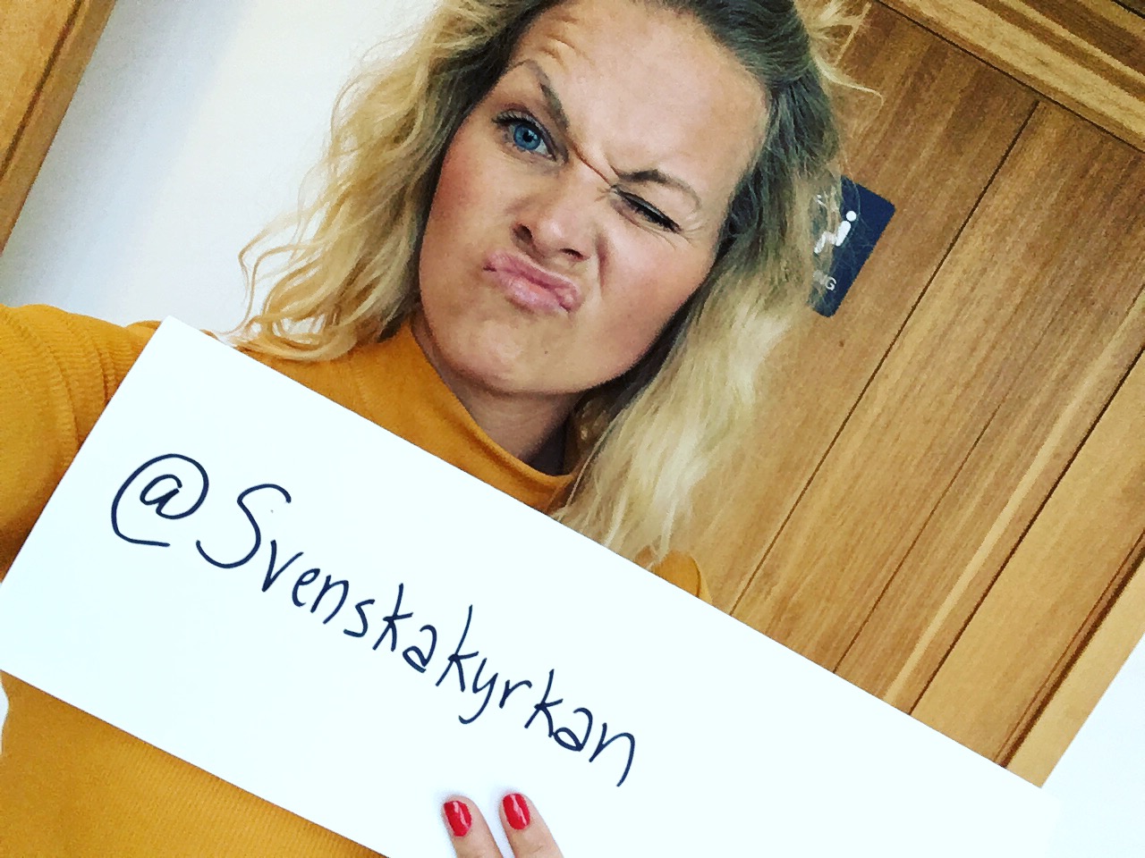 Närbild på Pernilla Ludvigsson med en skylt i handen på vilken det står @svenskakyrkan