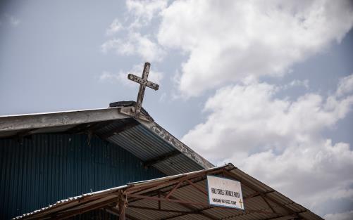 Ett kors på kyrktak mot blå himmel 