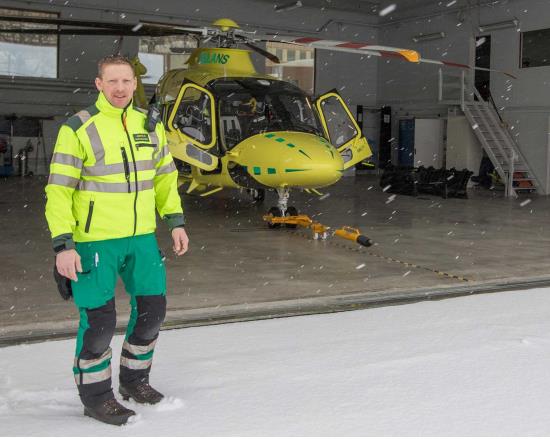 Sjuksköterska Johan Oscarsson framför ambulanshelikopter.