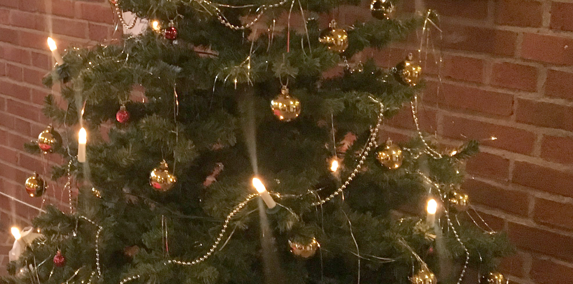 En julgran med elektriska lus och guldkulor.