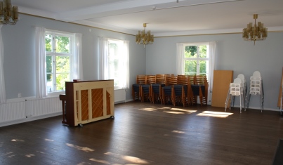Stora salen, med en orgel och stolar, även bebisstolar, uppställda mot väggen. 