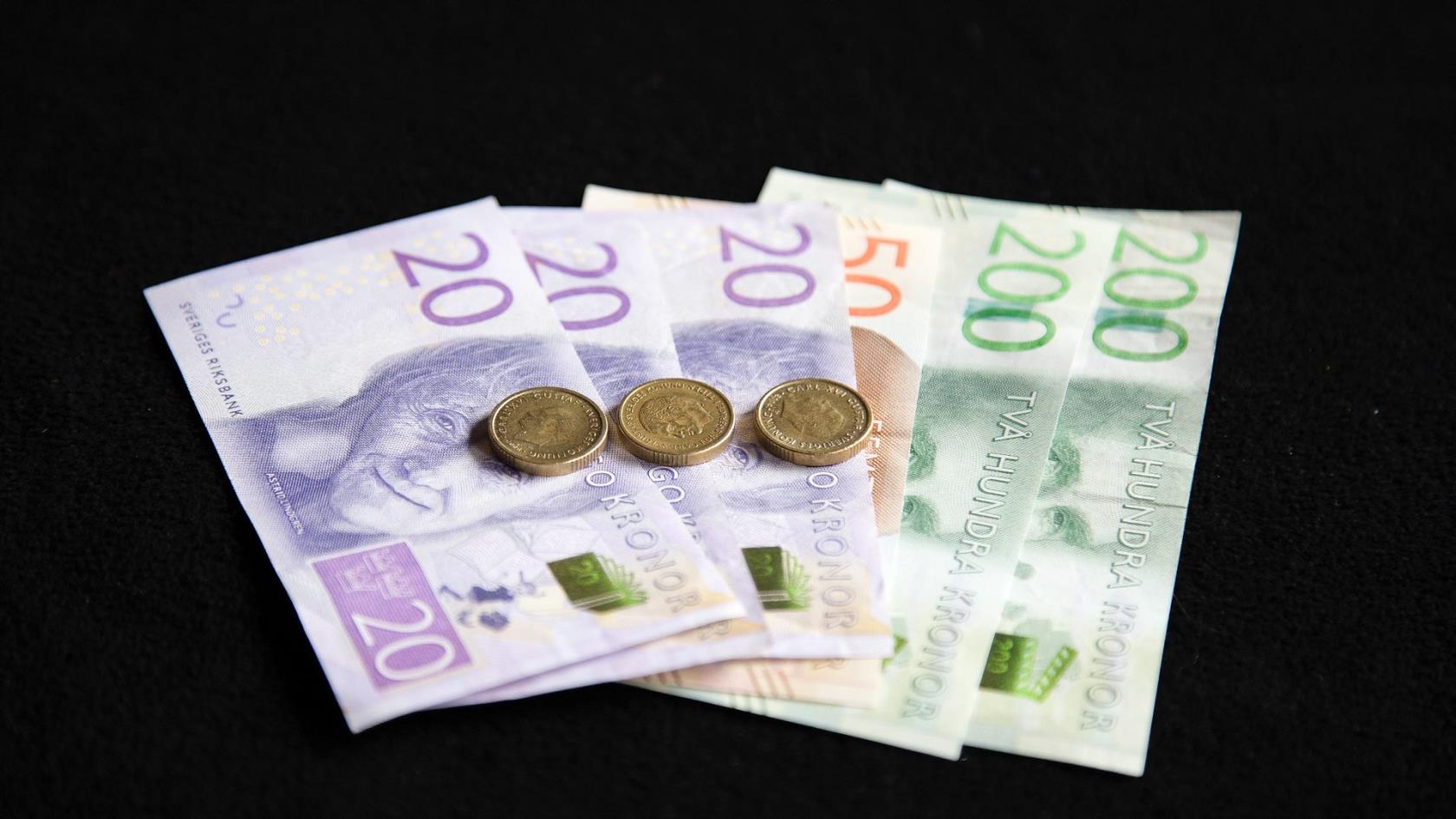 Svenska sedlar och mynt ligger på ett bord.