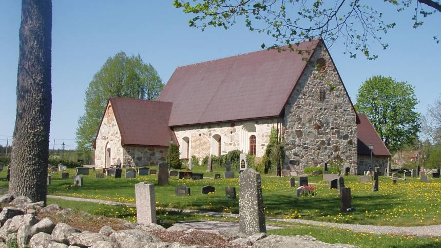 Frösunda kyrka med kyrkogård och gröna träd i bakgrunden.   