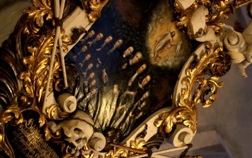 En tavla i Torshälla kyrka. Det är en guldfärgad ram med blad. Målningen föreställer två rader med svartklädda personer och några präster. Ovanför dessa ser man himlen med änglar.