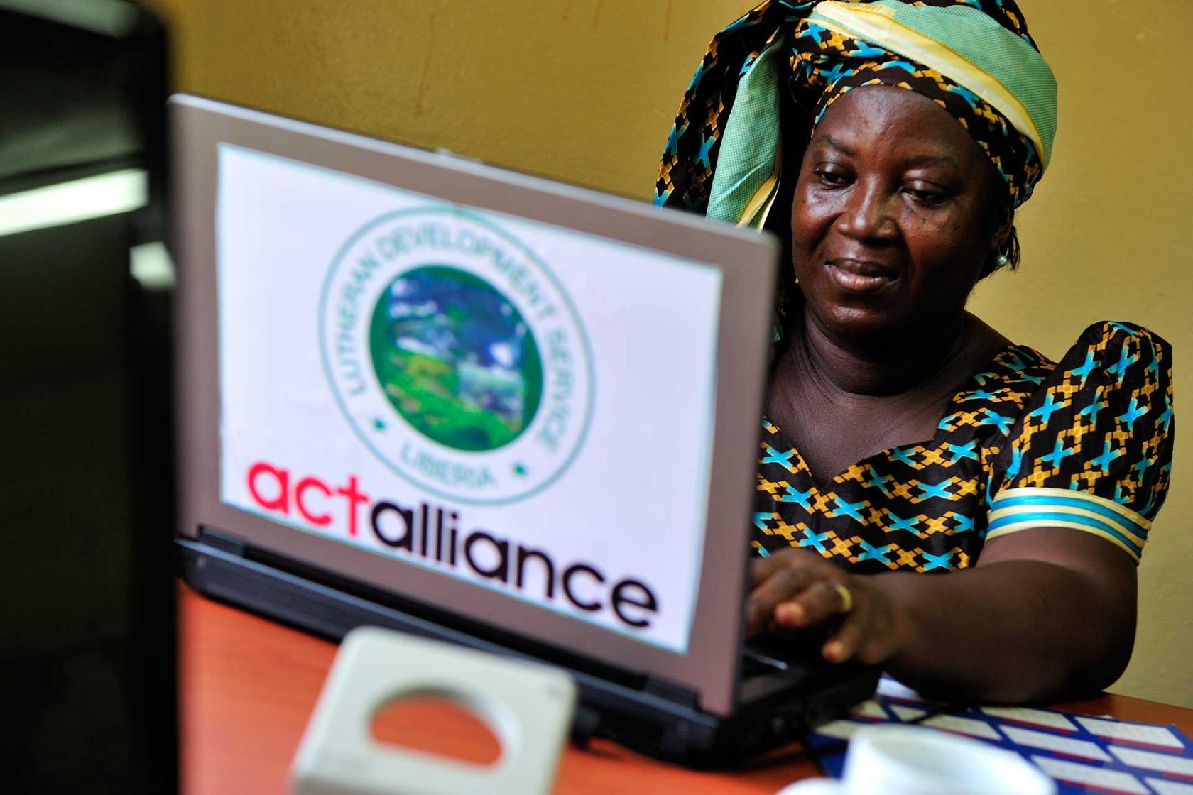 En kvinna sitter vid en dator, på datorn finns dekalen ACT-alliansen. 