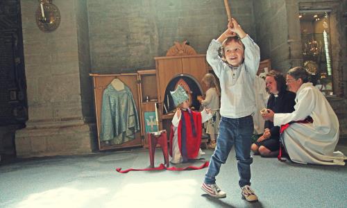 Barn leker med utklädnader i kyrka.